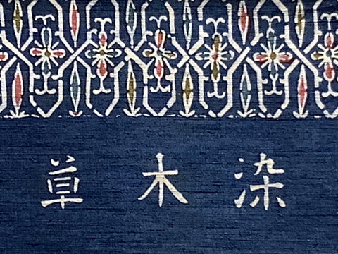 8147: Kusakizome silk, Close-up of a dark blue textile with a white geometric patterned border and three large white Japanese characters across the lower section, read as "kusakizome".