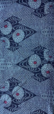 8114: 59in. 1970s Ohshima Tsumugi silk, geometric patterned textile featuring navy blue and light blue geometric diamond motifs with stylized floral or medallion shapes in pale blue and small red centers.