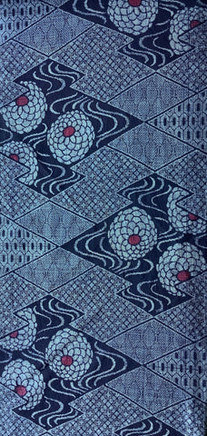 8114: 59in. 1970s Ohshima Tsumugi silk, geometric patterned textile featuring navy blue and light blue geometric diamond motifs with stylized floral or medallion shapes in pale blue and small red centers.