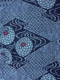 8114: 59in. closeup 2 1970s Ohshima Tsumugi silk, geometric patterned textile featuring navy blue and light blue geometric diamond motifs with stylized floral or medallion shapes in pale blue and small red centers.