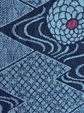 8114:  extra closeup- 1970s Ohshima Tsumugi silk, geometric patterned textile featuring navy blue and light blue geometric diamond motifs with stylized floral or medallion shapes in pale blue and small red centers.