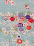 8140: 1960s Chirimen Japan Silk;A close-up of a light blue fabric with a traditional Japanese floral pattern featuring red, purple, pink, and green flowers and leaves.